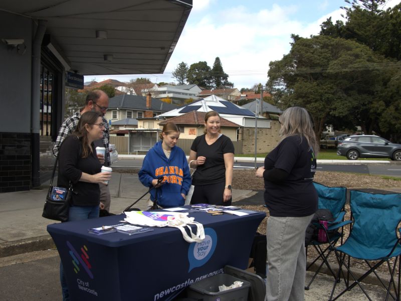 A number of community members are actively in conversation with a City of Newcastle staff member, who is facing away from the camera,  at Orchardtown Road.