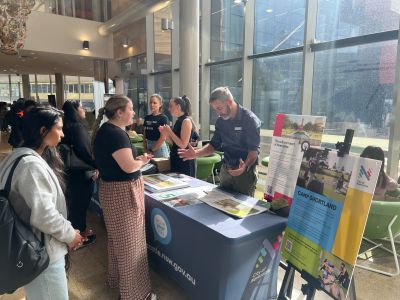A table set up indoors at NUSPACE. City of Newcastle staff are seen engaging in conversation with students.