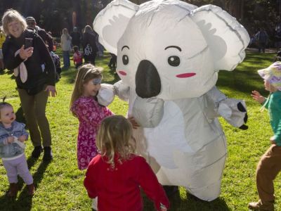 A person in an inflatable koala costume in conversation with a young child at Carnley Reserve